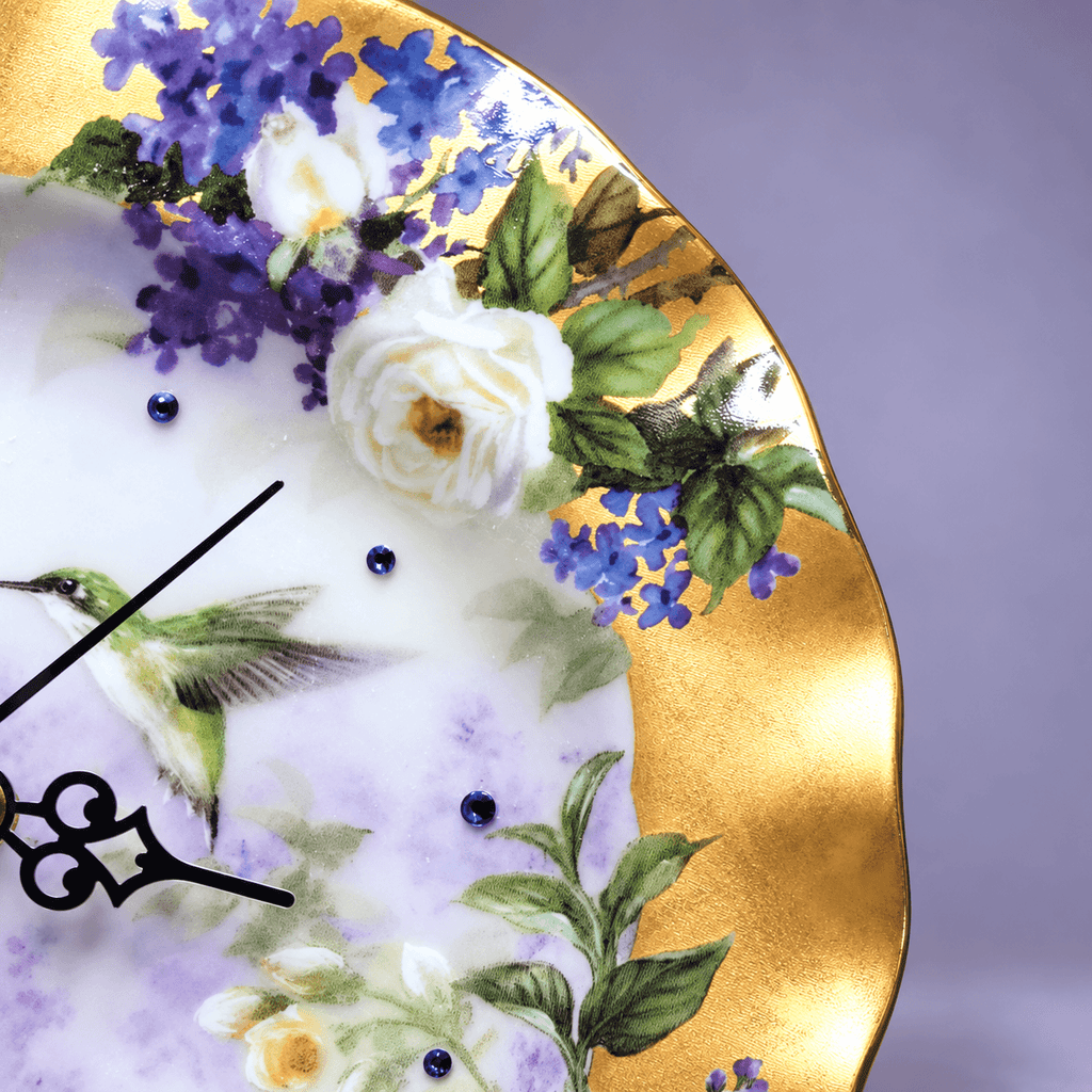 Hummingbird decorative plate clock with two hummingbirds, purple lilacs, ivory roses and sapphire-blue crystal hour markers