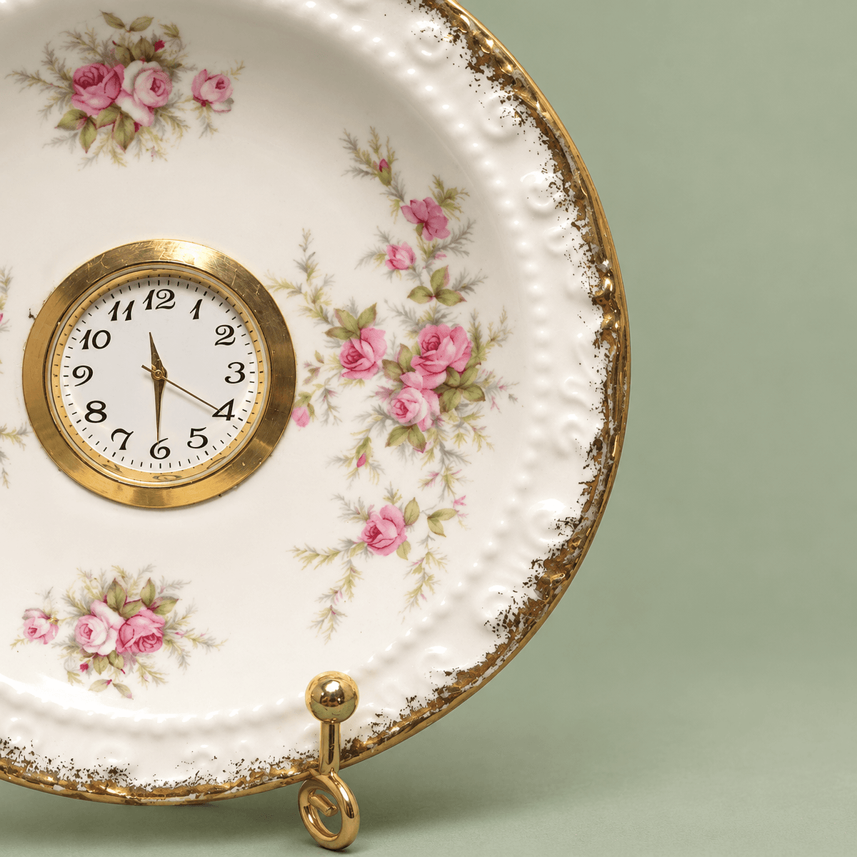Vintage floral plate clock showing delicate pink roses and soft green foliage