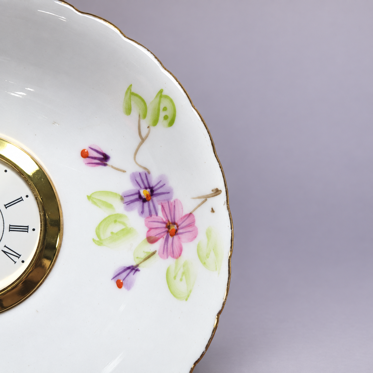 Close-up of the lavender floral plate clock with its gold-tone Roman numeral clock face