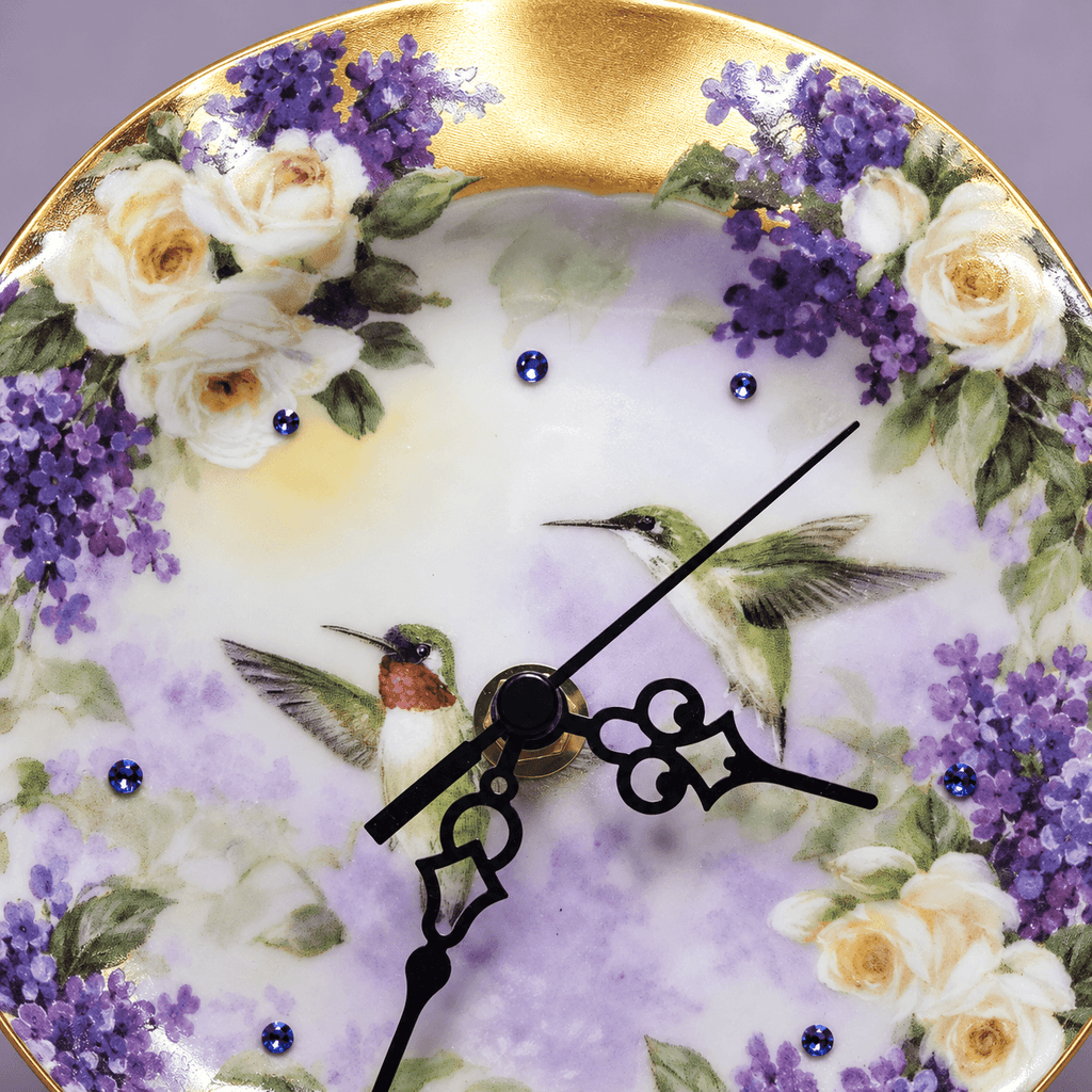 Hummingbird decorative plate clock with two hummingbirds, purple lilacs, ivory roses and sapphire-blue crystal hour markers
