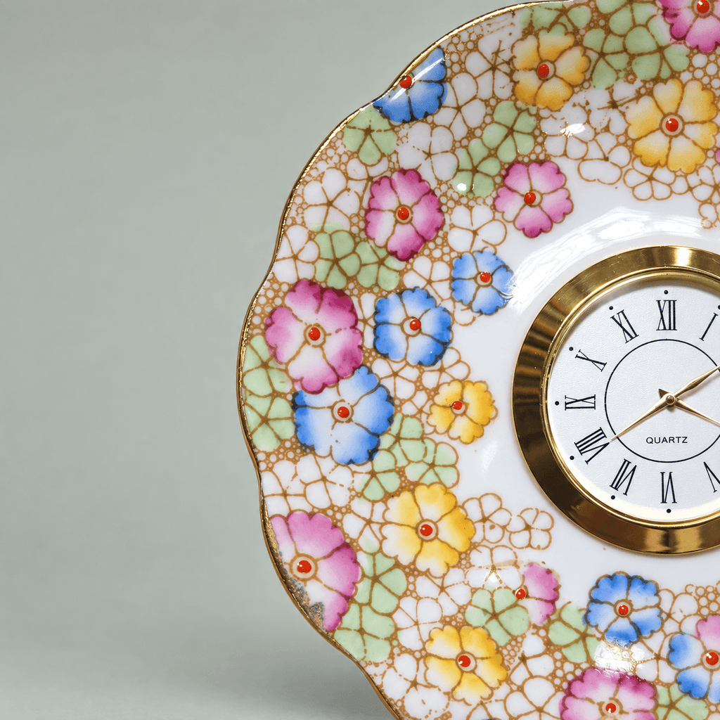 Pastel mosaic china plate clock with pink, blue and yellow flowers, mint-green accents and a gold Roman numeral clock face